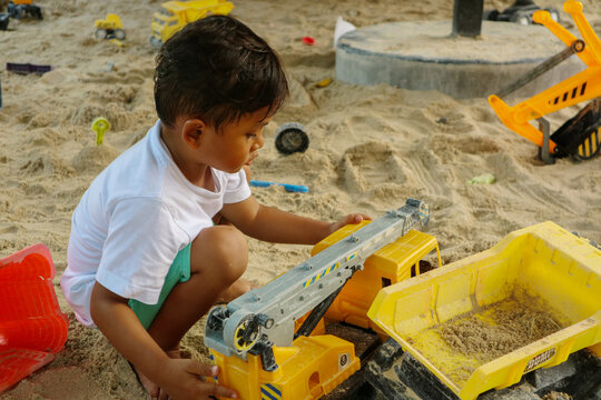 Asian boy play a toy of excavator with a sand on the beach, this immage can use for kid, toy, play and beach concept