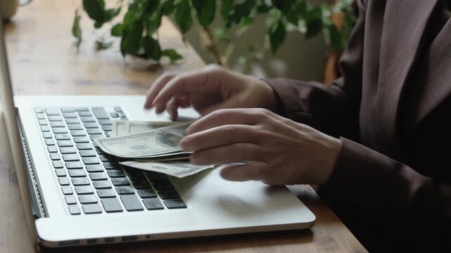 Business woman counting dollar bills sitting at desk in office. Passive income, savings, business investments.