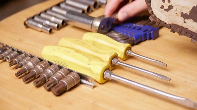 Maintenance of an old chainsaw. Choosing from a selection of hand tools.
