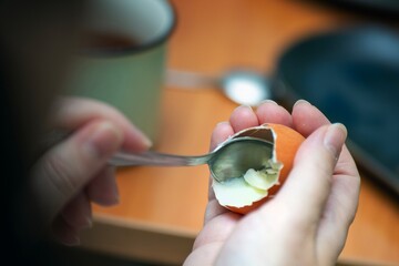 Metal teaspoon scooping the last remnants of boiled egg from its shell