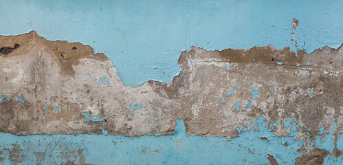 Horizontal dirty distressed cement wall with peeling light blue paint. Upper and lower parts of...