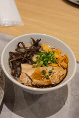 a small bowl of tonkatsu ramen with fried garlic and spring onions