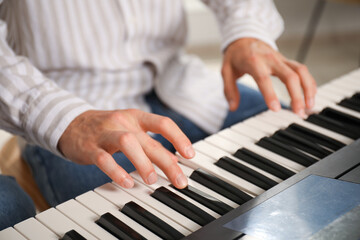 Man learning to play piano indoors, closeup © New Africa