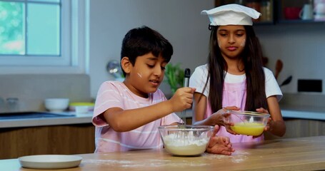 Indian Asian small sibling kids cooking with eggs and flour in modern kitchen, playful brother and sister mixing ingredients using spatula and utensils, learning baking, childhood fun - Powered by Adobe