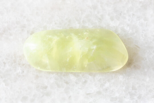 sample of tumbled vesuvianite rock on white marble