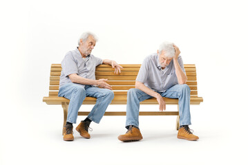 Senior man sitting on a bench and talking to a copy of himself