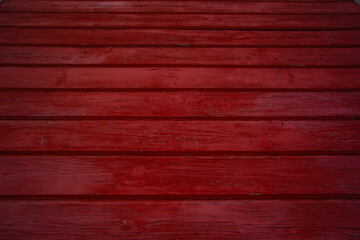 Close-up of red painted wooden planks with visible texture and grain. Rustic background for design, construction, or decorative use with strong bold color and natural wood details.