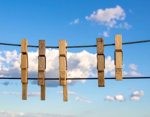 Obraz premium Wooden clothespins on a clothesline against a partly cloudy sky (1)