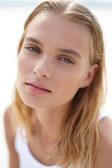 Naklejka premium Close-up portrait of a serene young woman with natural beauty, blonde hair, and captivating green eyes. Soft, bright light highlights her fresh, clear skin, perfect for lifestyle and beauty concepts.