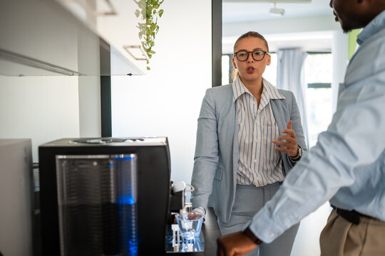 Business colleagues having serious discussion near office water cooler
