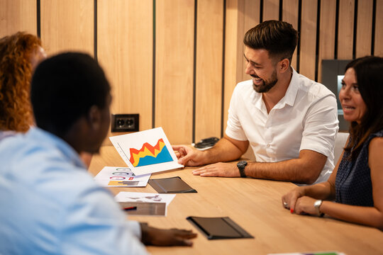 Business team meeting with diverse colleagues analyzing colorful financial charts