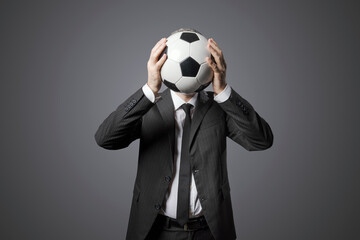 Businessman hiding his face behind a soccer ball