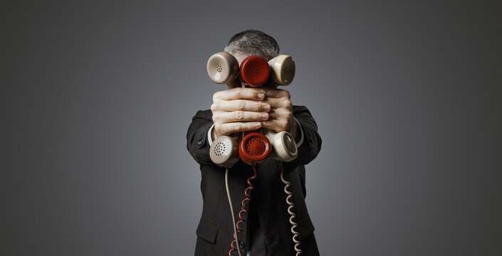 Office worker holding many telephone receivers - Powered by Adobe