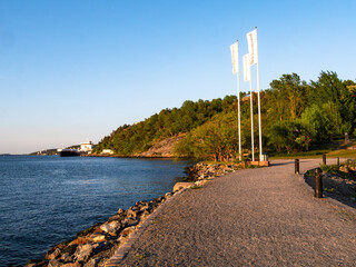 Scenic Waterfront Pathway with Flags and Green Hillside