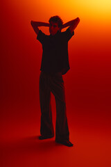 Stylish young man poses confidently against a vibrant orange backdrop