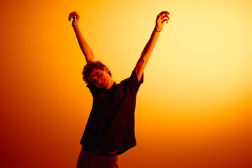 Handsome young man stretching under a warm orange light in stylish attire