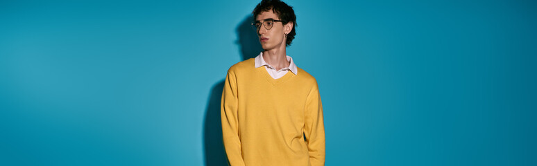 Stylish young man showcases modern fashion against a vibrant blue backdrop