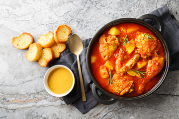 Chicken Bouillabaisse cooked in a delicious rich and fragrant broth closeup in the saucepan on the table. Horizontal top view from above