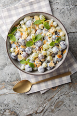 Sweet grape salad with almonds and mint with yogurt dressing close-up in a plate on the table. Vertical top view from above
