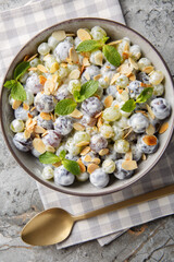 Close-up of grape mix salad with almonds dressed with creamy cheese sauce in a plate on the table. Vertical top view from above