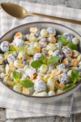 Freshly made grape salad with almonds and brown sugar sprinkled on top with creamy cheese dressing closeup in the plate on the table. Vertical