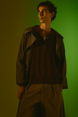 Handsome young man showcasing stylish attire against a vibrant green backdrop