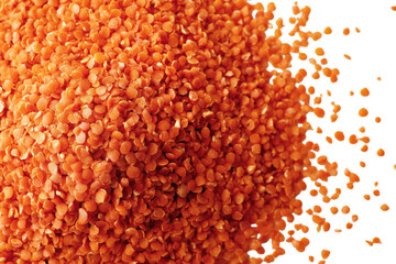 Close up view of vibrant orange lentils poured against a transparent background