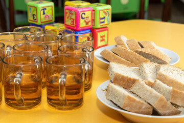 Kids enjoy a snack time with tea and bread at a vibrant classroom during morning break