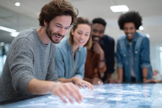 Diverse team collaborates using interactive display. Innovation, technology, and teamwork merge in this scene. Perfect for illustrating data analysis, strategy, and future tech.