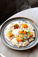 Creamy mushroom risotto served with roasted pumpkin and fresh herbs on a rustic plate.