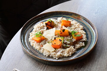 Top view of creamy mushroom risotto served with roasted pumpkin, colorful seasonal dish on a rustic table.