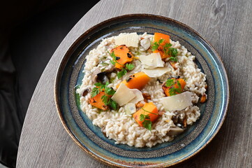 Creamy mushroom risotto served with roasted pumpkin and fresh herbs on a rustic plate.