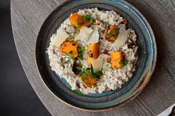 Creamy mushroom risotto served with roasted pumpkin and fresh herbs on a rustic plate.