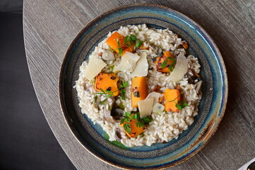 Creamy mushroom risotto served with roasted pumpkin and fresh herbs on a rustic plate.