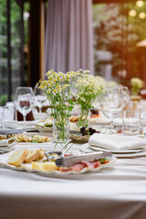 An elegantly decorated banquet table with delicious food and fresh chamomile centerpieces.