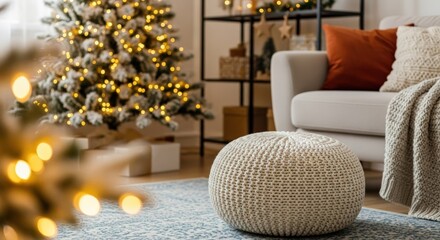 Cozy living room with a knitted pouf and a beautifully decorated Christmas tree with warm lights in the background.