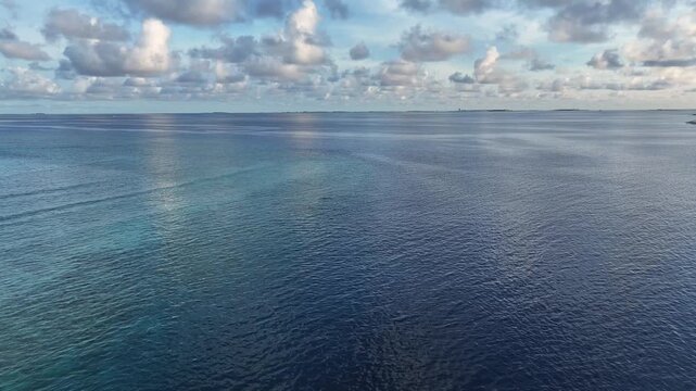 Aerial view of the ocean's surface with dolphins in the distance, creating a mesmerizing contrast, Gulhi, South Male Atoll, Maldives.