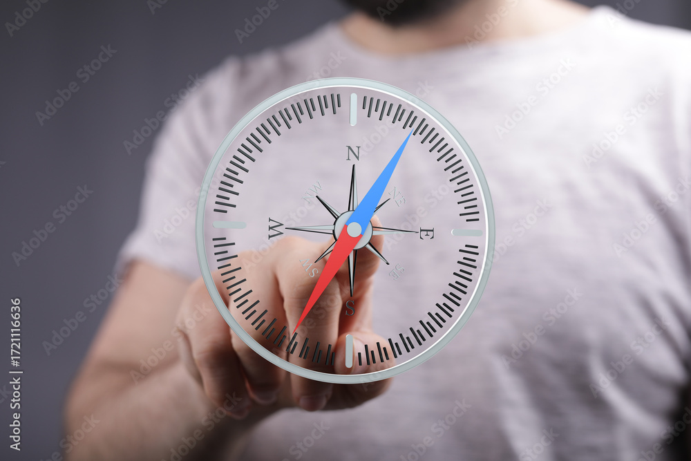 Poster close-up of a person's hand interacting with a digital compass interface, symbolizing guidance and d