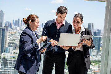 Business team working together on a laptop during an outdoor or rooftop office meeting	