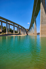 Tranquil scenery under a bridge over a reservoir with crystal clear turquoise water