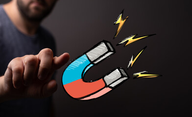 Hand reaching for a powerful magnet, symbolizing attraction, influence, and marketing success.