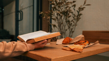 Reading a book at a cafe with pastries and autumn leaves