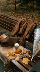 Autumn picnic scene on a park bench with coffee and pastry