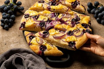 Eating Focaccia with red onion, brie cheese and strawberry grape, homemade flat leavened oven-baked...