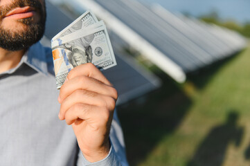 Man holding money with solar panels in background