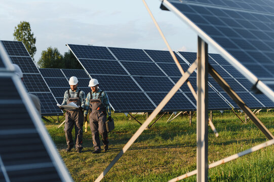 Engineers inspecting solar panels at renewable energy solar farm