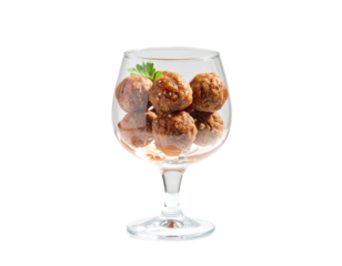 Several savory meatballs in a clear glass wine goblet, garnished with parsley