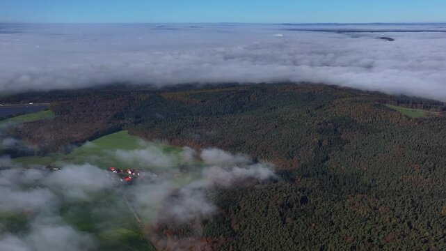 Aerial view of a landscape with lush green fields, dense forests, and a blanket of clouds in the distance, creating a serene and picturesque scene, Eichenzell, Hessen, Germany.