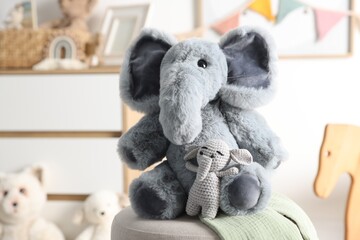 Cute soft toy elephants on pouf in child's room, closeup