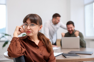 Woman feeling jealous of her colleague's success in office, selective focus